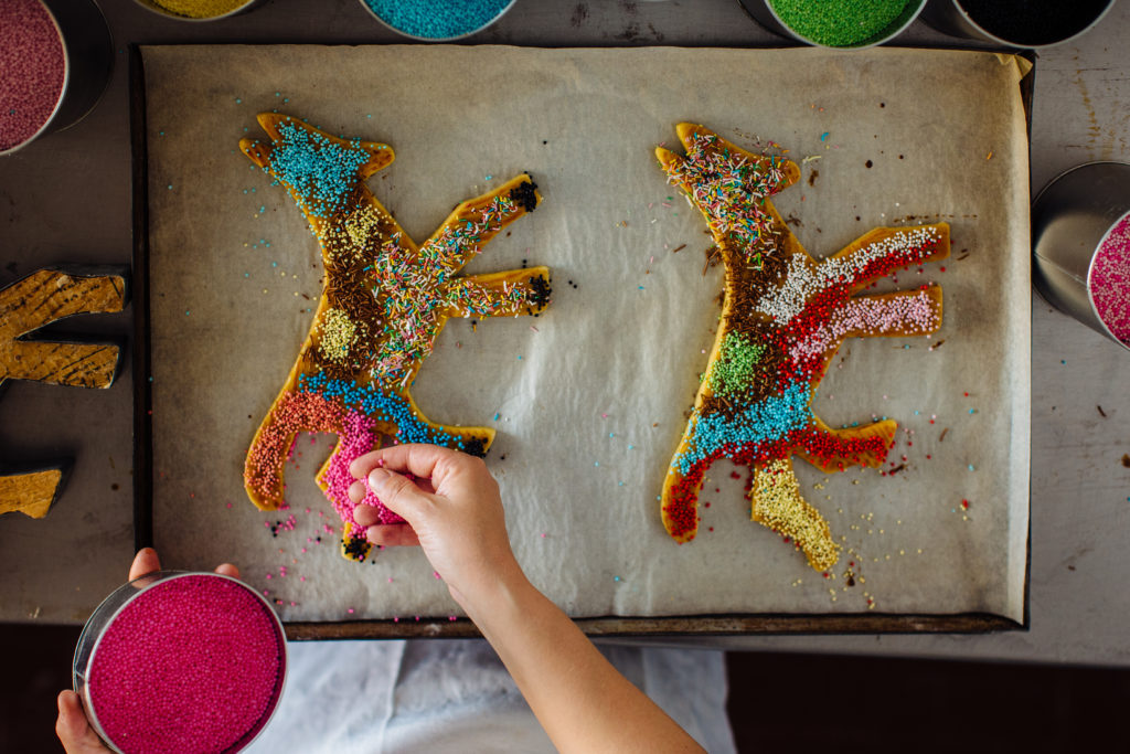 Girl putting sprinkles on biscuits